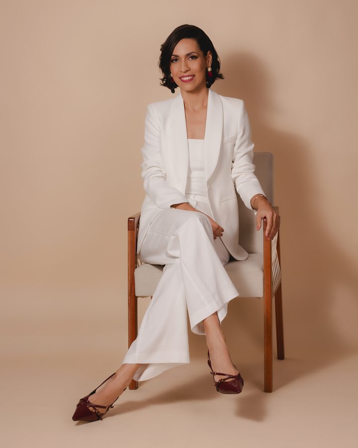 Dra. Cinara Costa sentada, de terno branco